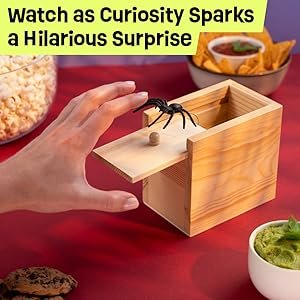 A hand being attacked by the spider coming out of the box on a table of food